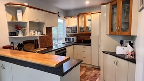 A compact kitchen with white cabinets, a wooden countertop, and a microwave.