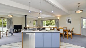 Un salón espacioso con una isla central, una mesa de comedor y un televisor.