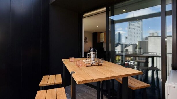 A wooden table with benches on a balcony with a city view. - Worcester Terrace 201 - Luxurious City Apartment (Christchurch)