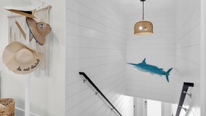 Et værelse med hvid væg, en flettet kurv, en hat, en loftlampe og en hajtæppe.