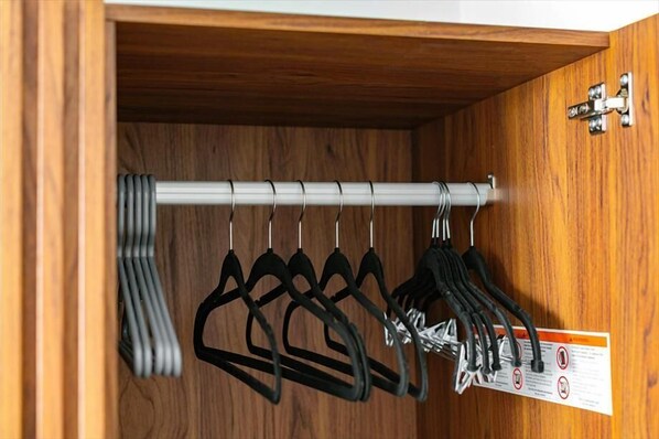 A wooden closet with a metal rod and black hangers.