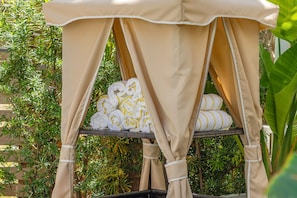 A covered outdoor seating area with rolled towels and a wicker table.