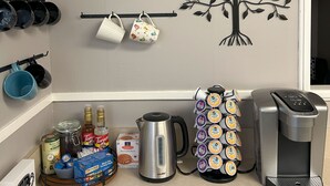 Una encimera de cocina con cafetera, hervidor y dispensador de cápsulas de café.