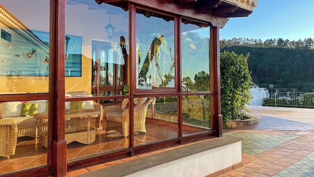 A covered outdoor seating area with wicker furniture and a view of a mountainous landscape. - Villas el Alto (Moya)