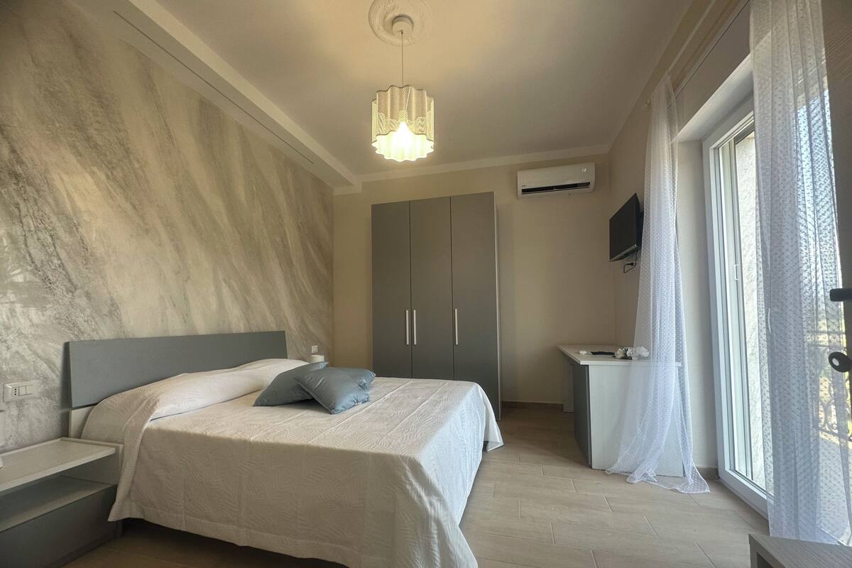 A bedroom with a bed, nightstands, a wardrobe, a desk, and a TV.