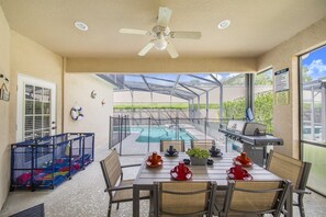 A covered patio with a pool, a grill, and a table set for dining. - 4bed pool /Hot tub,Game Room at Calabay Tower lake (Haines City)