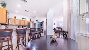 Une cuisine moderne avec des meubles de rangement en bois, une table à manger avec des chaises et un saladier décoratif.