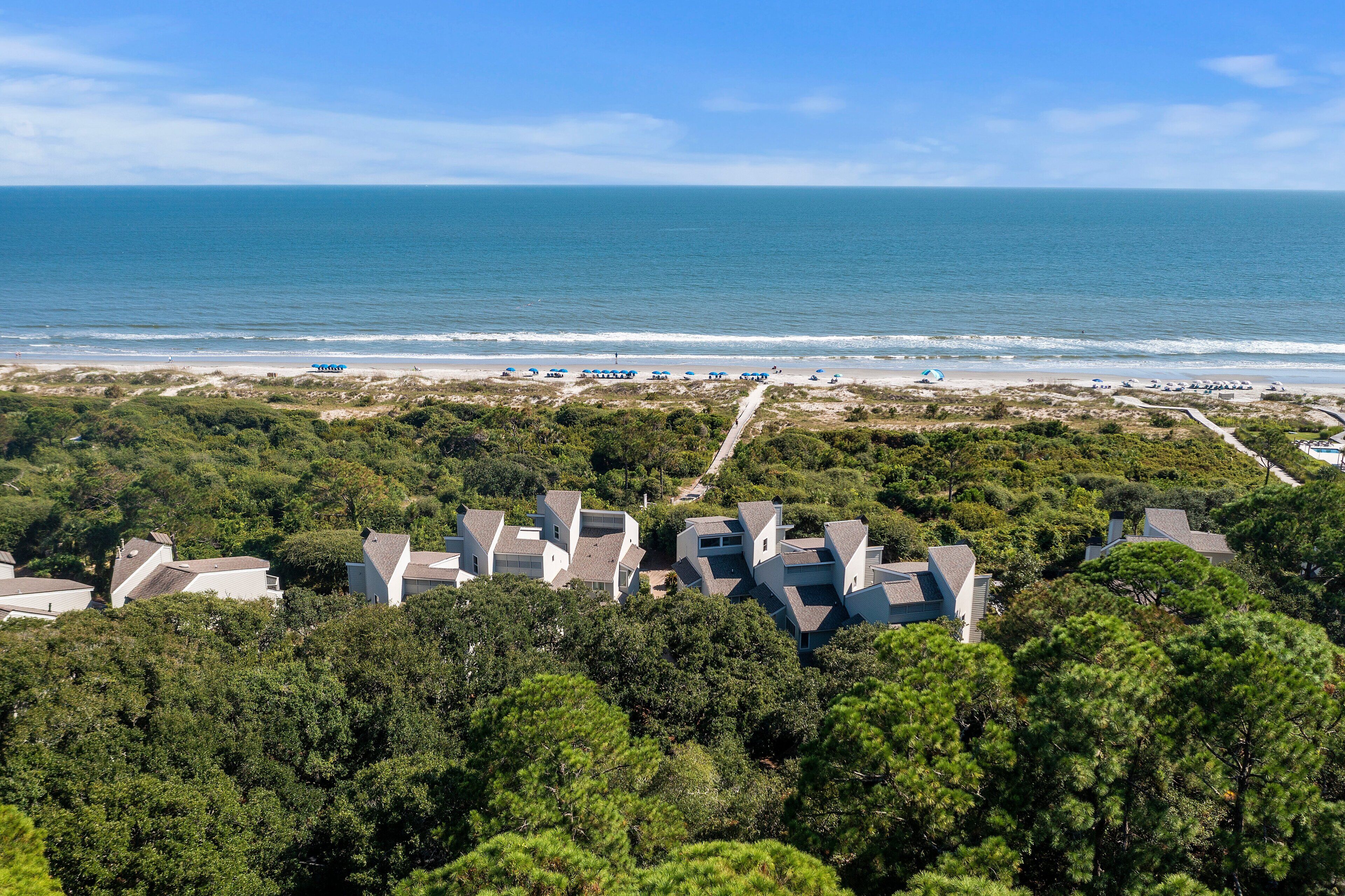 A coastal residential area with houses, a beach, and a clear sky.