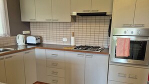 A kitchen with white cabinets, a gas stove, a built-in oven, and a tiled backsplash. -  Nannup Riverview Cottage, fully Self Contained Holiday Let (Nannup)