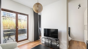 A modern living room with a flat-screen TV, a black coffee table, and a sofa. - Royal Wilanów Chic Studio (Warszawa)