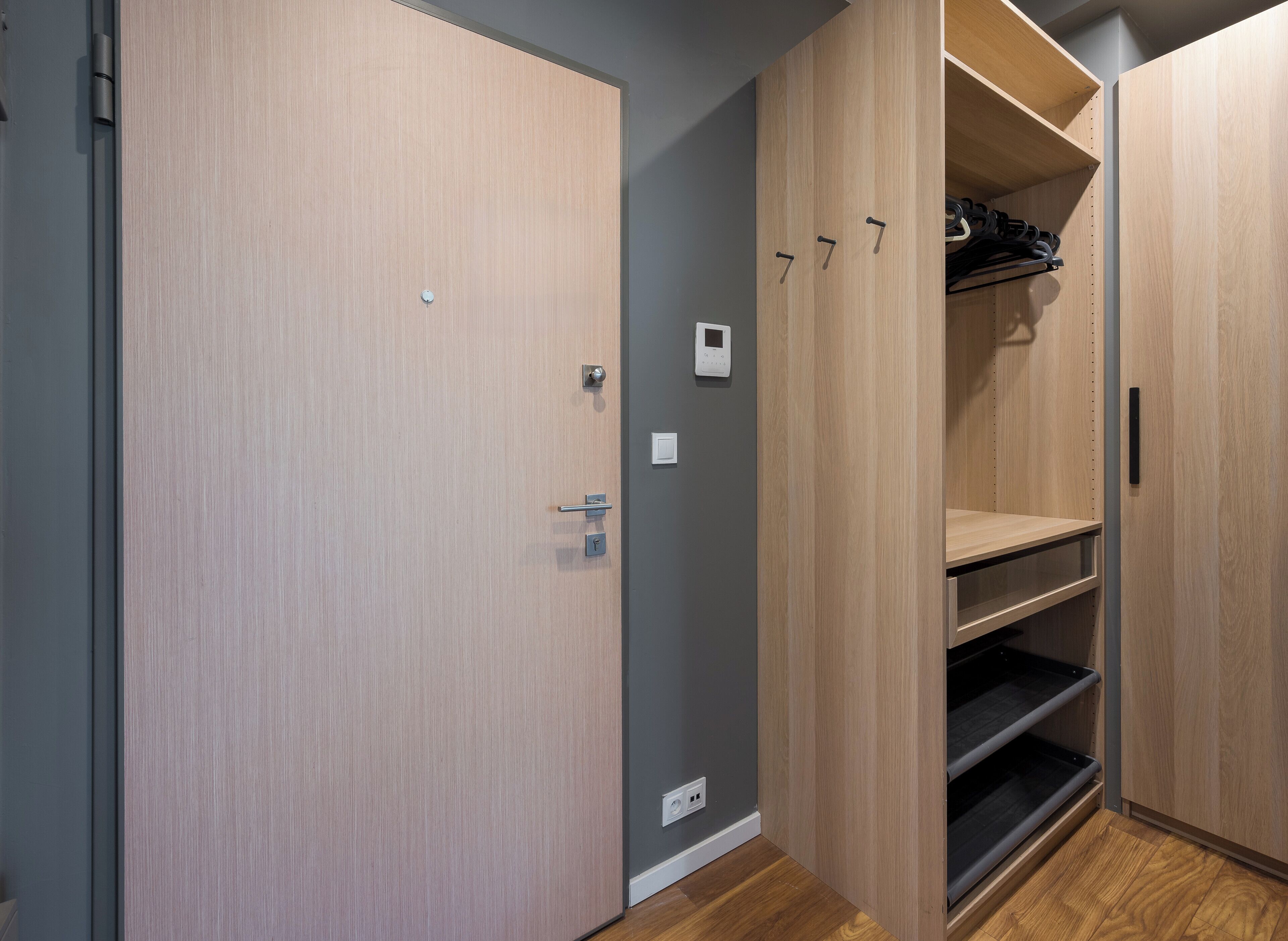A modern closet with wooden doors, a built-in shelf, and a hanging rack.