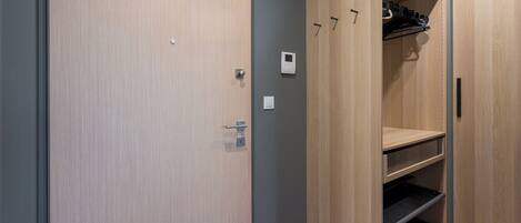 A modern closet with wooden doors, a built-in shelf, and a hanging rack.