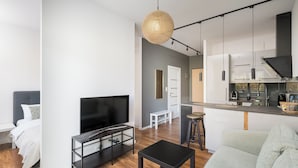 A modern apartment with a TV, sofa, dining area, kitchen, and a hanging light fixture. - Royal Wilanów Chic Studio (Warszawa)