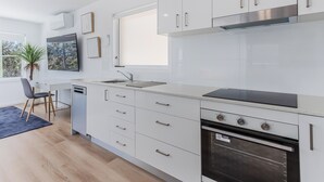 Una cocina moderna con gabinetes blancos, horno de acero inoxidable y lavavajillas integrado.