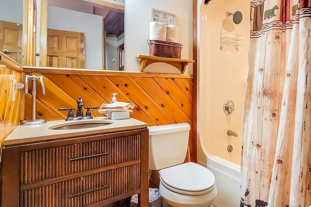 A bathroom with a wooden vanity, a toilet, and a shower curtain with animal prints.