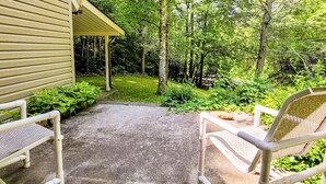 Un portico coperto con due sedie, immerso nel verde e alberi.