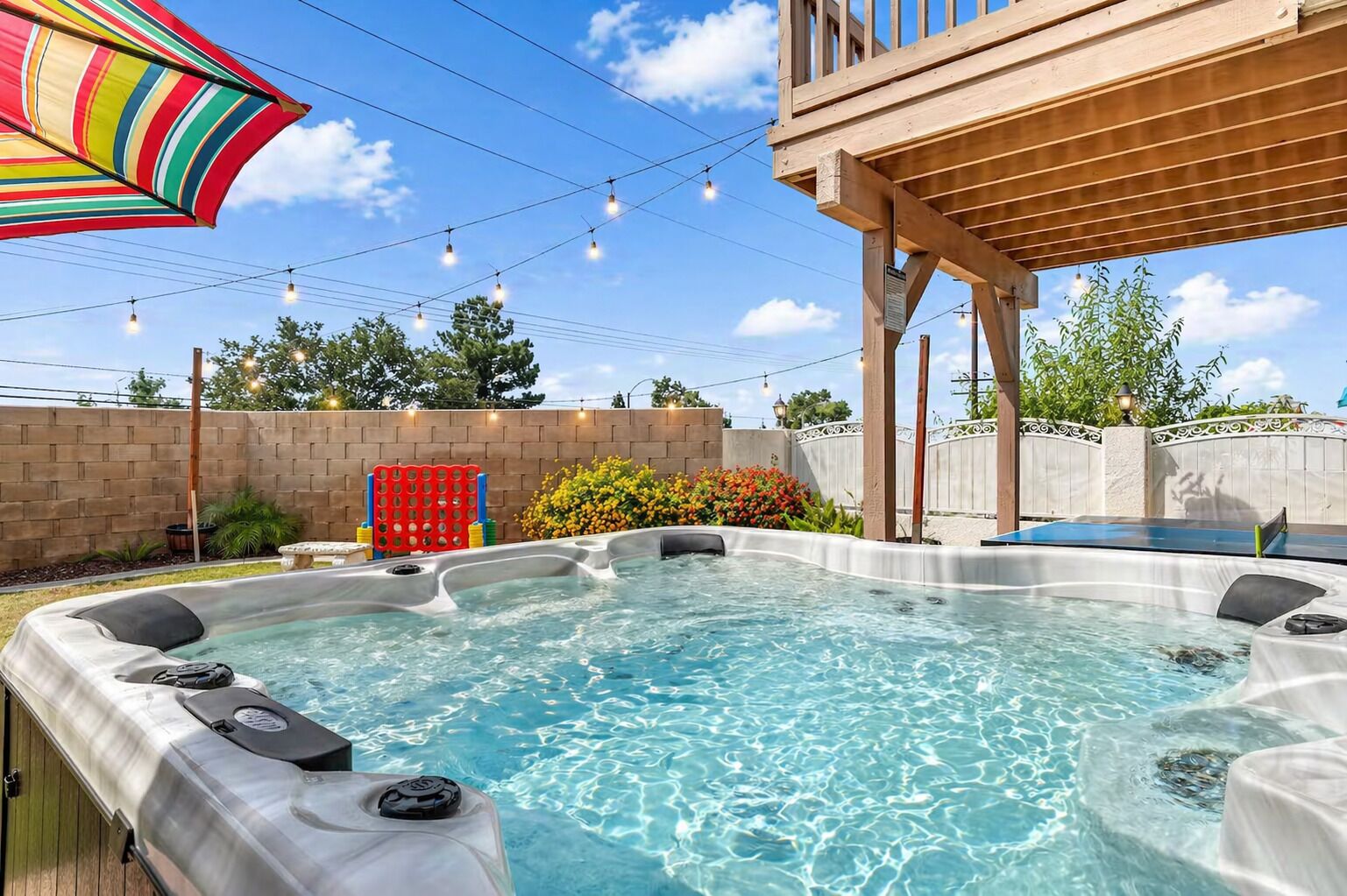 A hot tub with a wooden deck and a colorful umbrella.