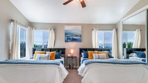 A bedroom with two beds, a ceiling fan, a painting, and a view of the outdoors. - Serenity Villa Hermosa, Jacuzzi, Arcade & Fun Games, Backyard, Outdoor Furniture (Moreno Valley)