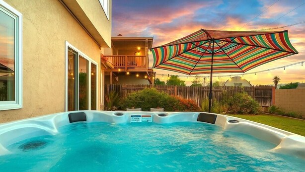 A hot tub with a wooden deck and a colorful striped umbrella. - Serenity Villa Hermosa, Jacuzzi, Arcade & Fun Games, Backyard, Outdoor Furniture (Moreno Valley)