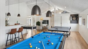 A spacious indoor recreational area with a pool table, foosball table, and a dartboard.
