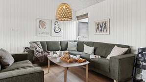 A modern living room with a grey sectional sofa, a small white coffee table, and a wicker pendant light.