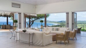 A spacious living area with a large sofa, chairs, and a coffee table, overlooking a scenic ocean view. - Stunning Brand New Villa with Ocean & Mountain Views, Just a Minute's Drive to Tamarindo Beach (Tamarindo)