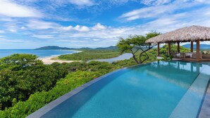 An infinity pool with a view of the ocean and a thatched-roof structure. - Stunning Brand New Villa with Ocean & Mountain Views, Just a Minute's Drive to Tamarindo Beach (Tamarindo)