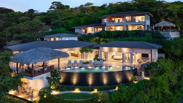 Uma villa luxuosa com uma piscina grande, vários quartos e um jardim bem cuidado.