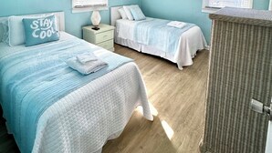 A bedroom with two beds, a ceiling fan, and a window with blinds. - Tiki Tides OBX 4-Bedroom Beach Box in Kill Devil Hills, Steps from the Beach! (Kill Devil Hills)