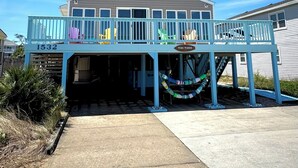A two-story building with a balcony, a sign reading "TIKI TIDES", and the number 1532 on the side. - Tiki Tides OBX 4-Bedroom Beach Box in Kill Devil Hills, Steps from the Beach! (Kill Devil Hills)