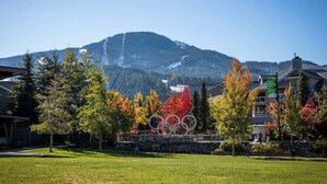 A hotel with a view of mountains and Olympic rings sculpture. - 1BR | Gondola Village | Near Gondola | Free Parking | Updated Unit | Incredible Location (Whistler)