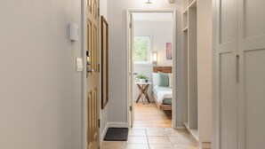 A hallway leading to a bedroom with a bed, bedside table, and a window. - 1BR | Gondola Village | Near Gondola | Free Parking | Updated Unit | Incredible Location (Whistler)