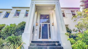 A white building with a central entrance, flanked by windows and a small porch area. - StayAU Expansive 7BR Villa Warrandyte (Warrandyte)