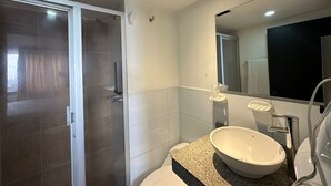 Un baño moderno con un espejo grande, un lavabo blanco y una zona de ducha.