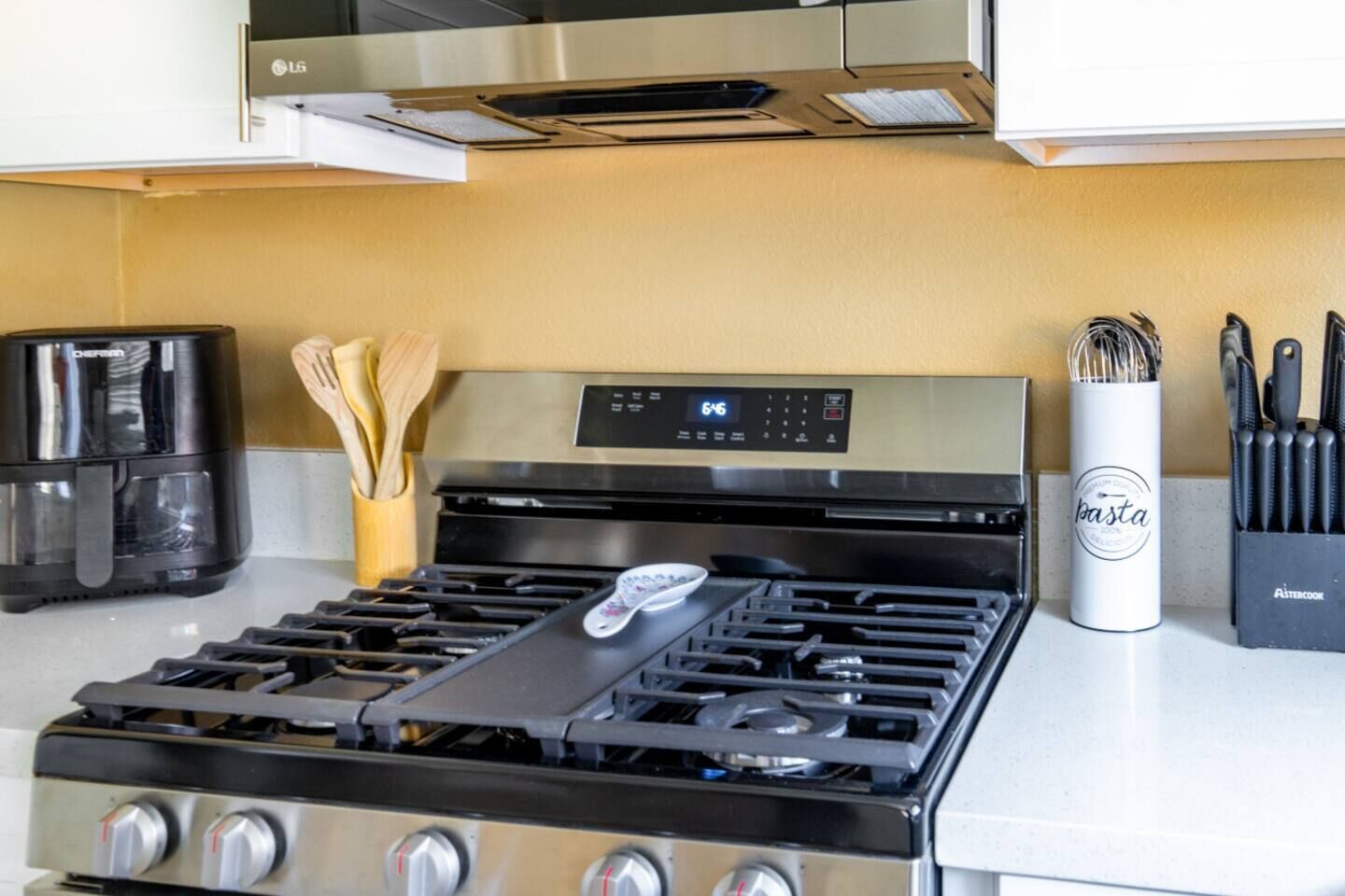 Una cocina con estufa, cafetera y bloque de cuchillos.