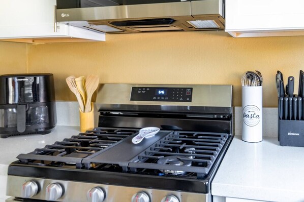 Une cuisine équipée d’une cuisinière, d’une machine à café et d’un bloc à couteaux.