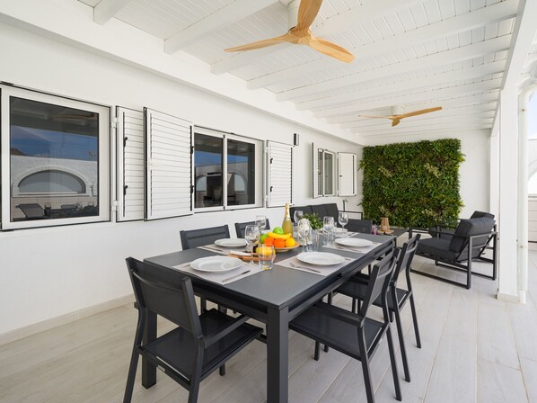 A dining area with a long table, black chairs, and a ceiling fan.