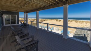 Une terrasse couverte avec un plancher en bois et vue sur la plage.