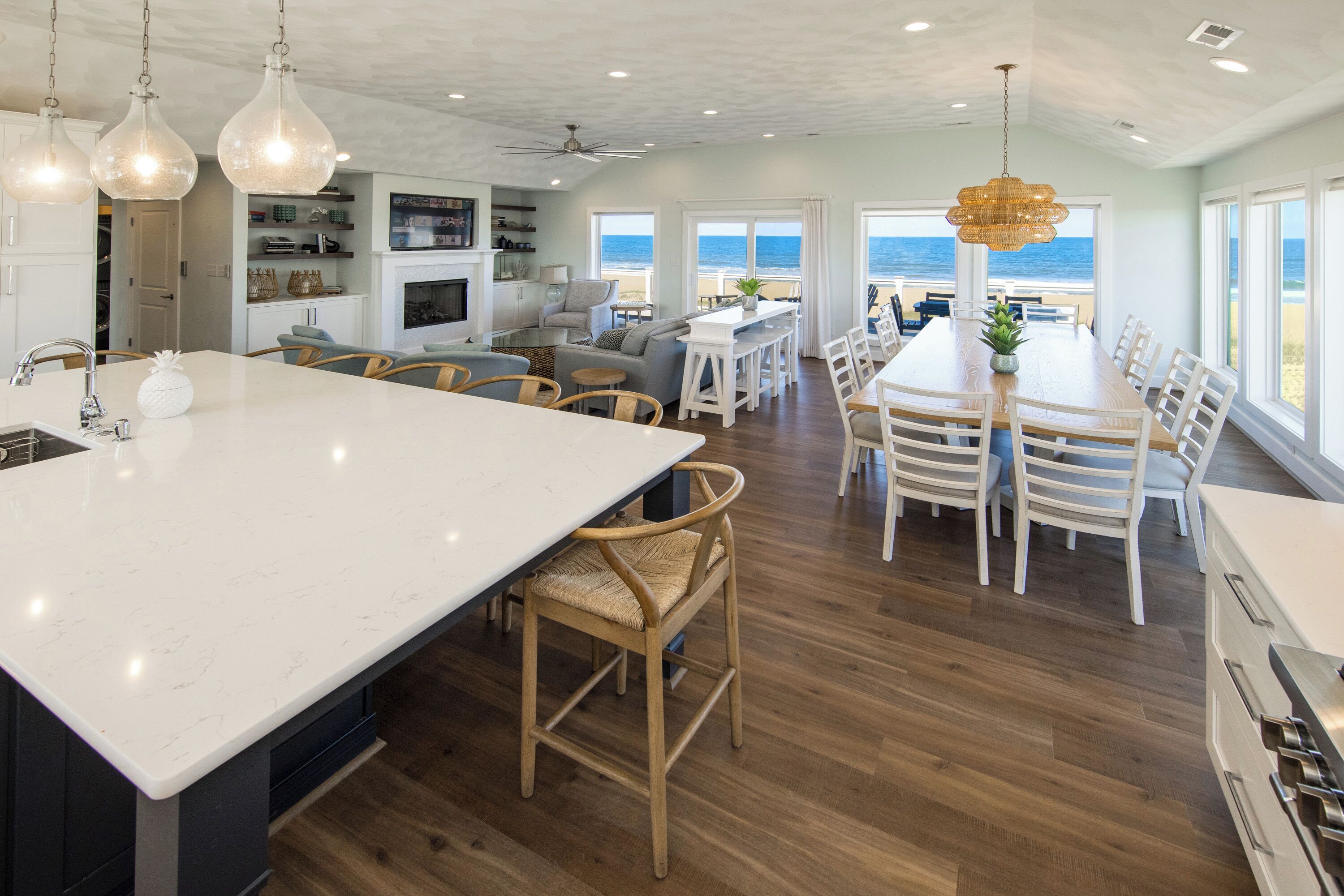A spacious kitchen with a large island, wooden chairs, and a view of the ocean.
