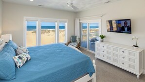 Une chambre avec un grand lit, une télévision et une vue sur la plage.
