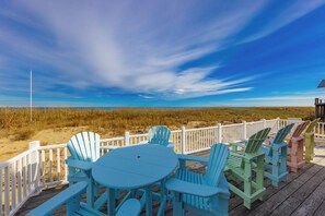 Eine Terrasse mit Tisch und Stühlen mit Blick auf einen Strand.