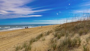 Ein Strand mit Dünen und blauem Himmel.
