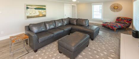 A modern living room with a sectional sofa, a colorful armchair, a coffee table, and a rug.