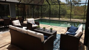 Un espace extérieur abrité avec une piscine, des meubles en osier et une vue sur les arbres.
