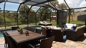Un espace extérieur abrité, doté d’une piscine, de meubles en osier et offrant une vue sur le paysage environnant.