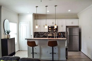 A modern kitchen with white cabinets, a stainless steel refrigerator, and pendant lighting. - Stylish 3BR Designer Duplex  Minutes to NRG, Med Center & Downtown (Houston)
