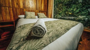 A bed with a floral-patterned bedspread and a rolled towel on it. - HOSTERIA KUMBHA MELA (Mindo)
