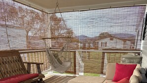 A wooden deck with a wicker sofa and a hanging hammock.