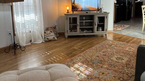 A living room with a sofa, a television, a patterned rug, and a ceiling fan.