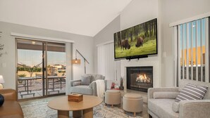 Una sala de estar moderna con chimenea, un televisor de pantalla plana y un ventanal corredizo que da a un patio exterior.